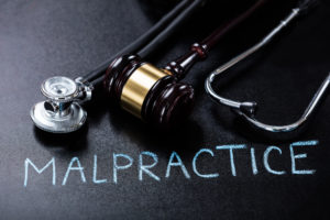 Malpractice Concept Showing Gavel And Stethoscope On Blackboard